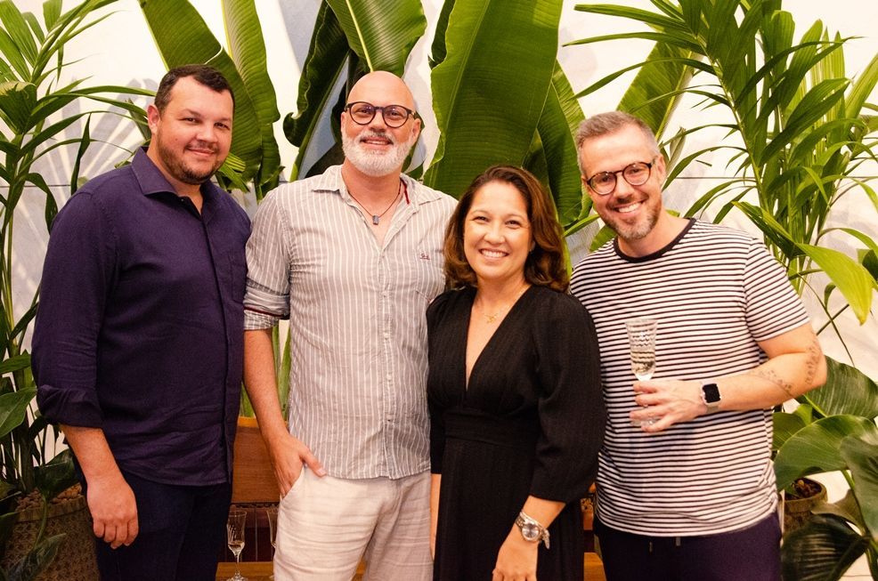 Um grupo de pessoas está posando para uma foto em frente às plantas.