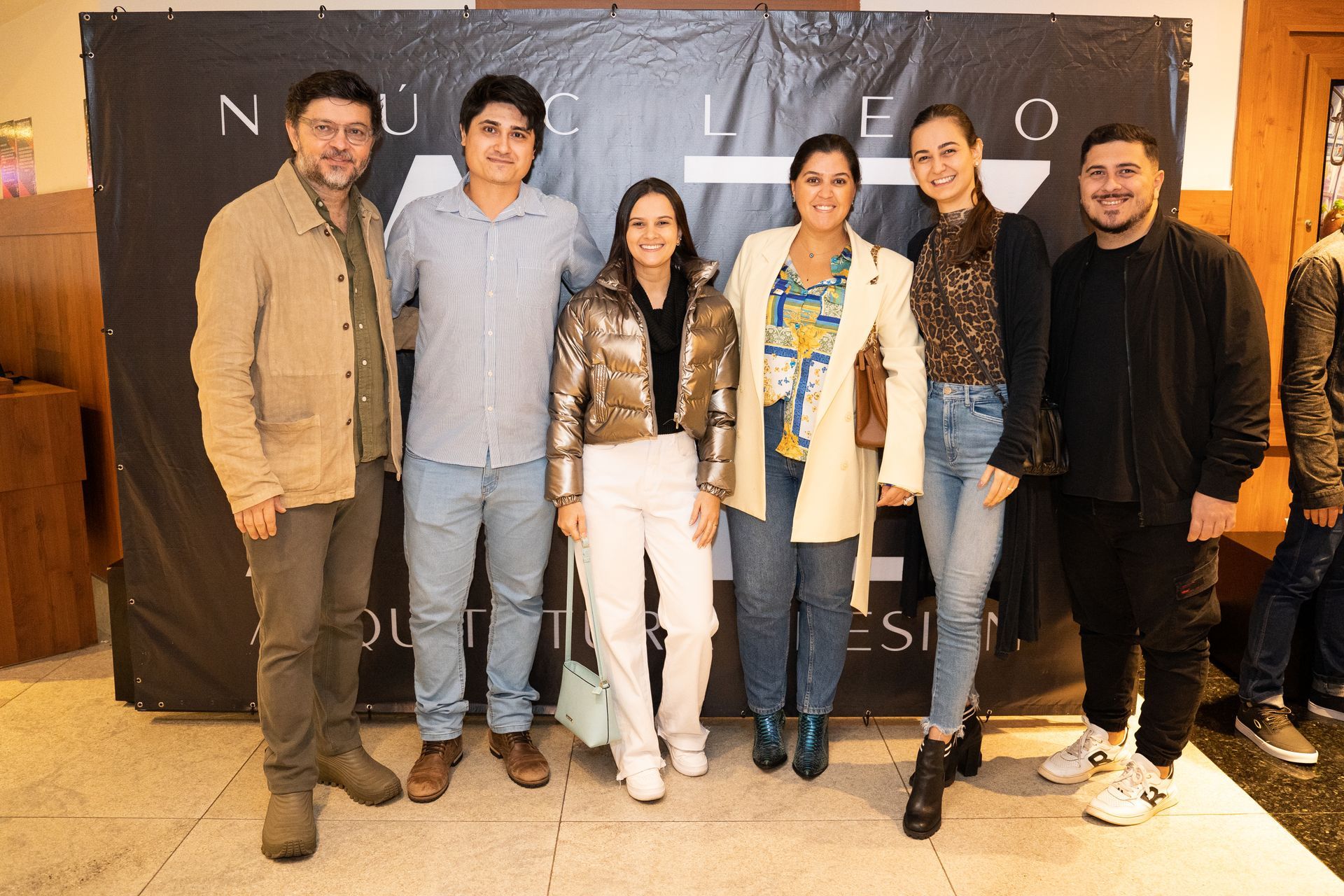 Um grupo de pessoas está posando para uma foto em frente a um banner.