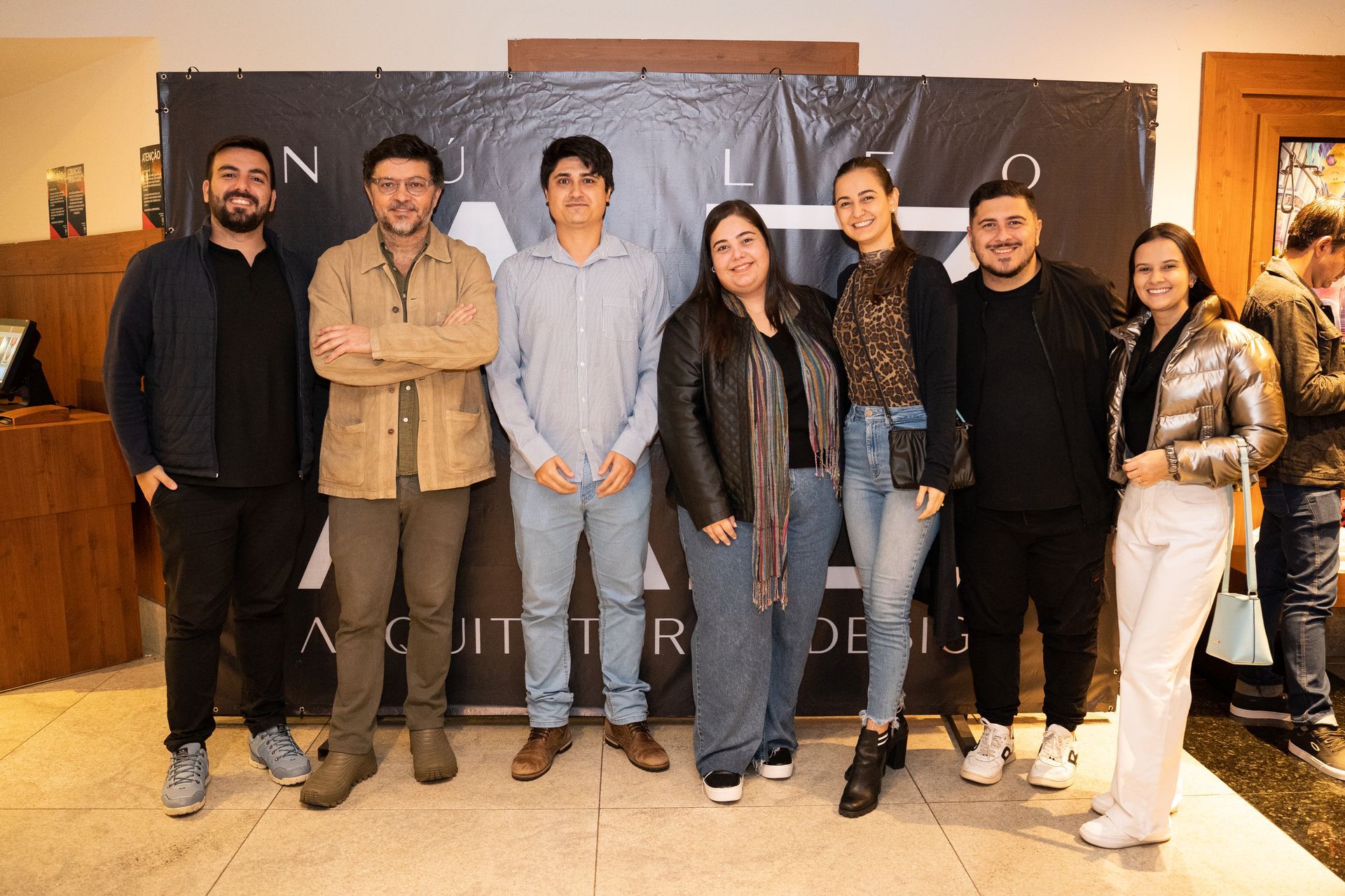 Um grupo de pessoas está posando para uma foto em frente a uma placa.