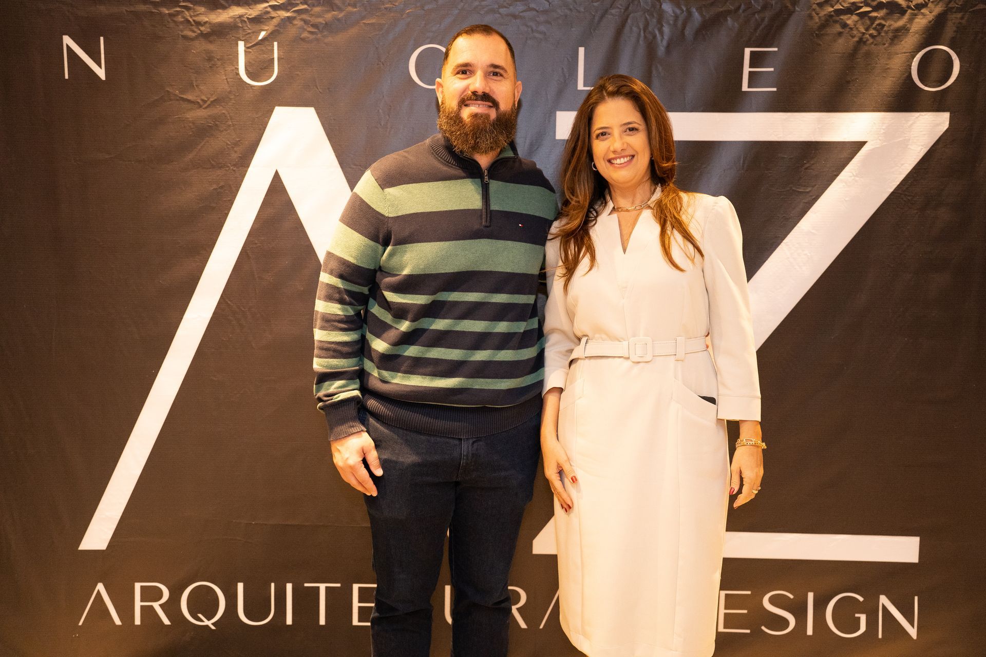 Um homem e uma mulher estão posando para uma foto em frente a uma placa que diz arquitet design