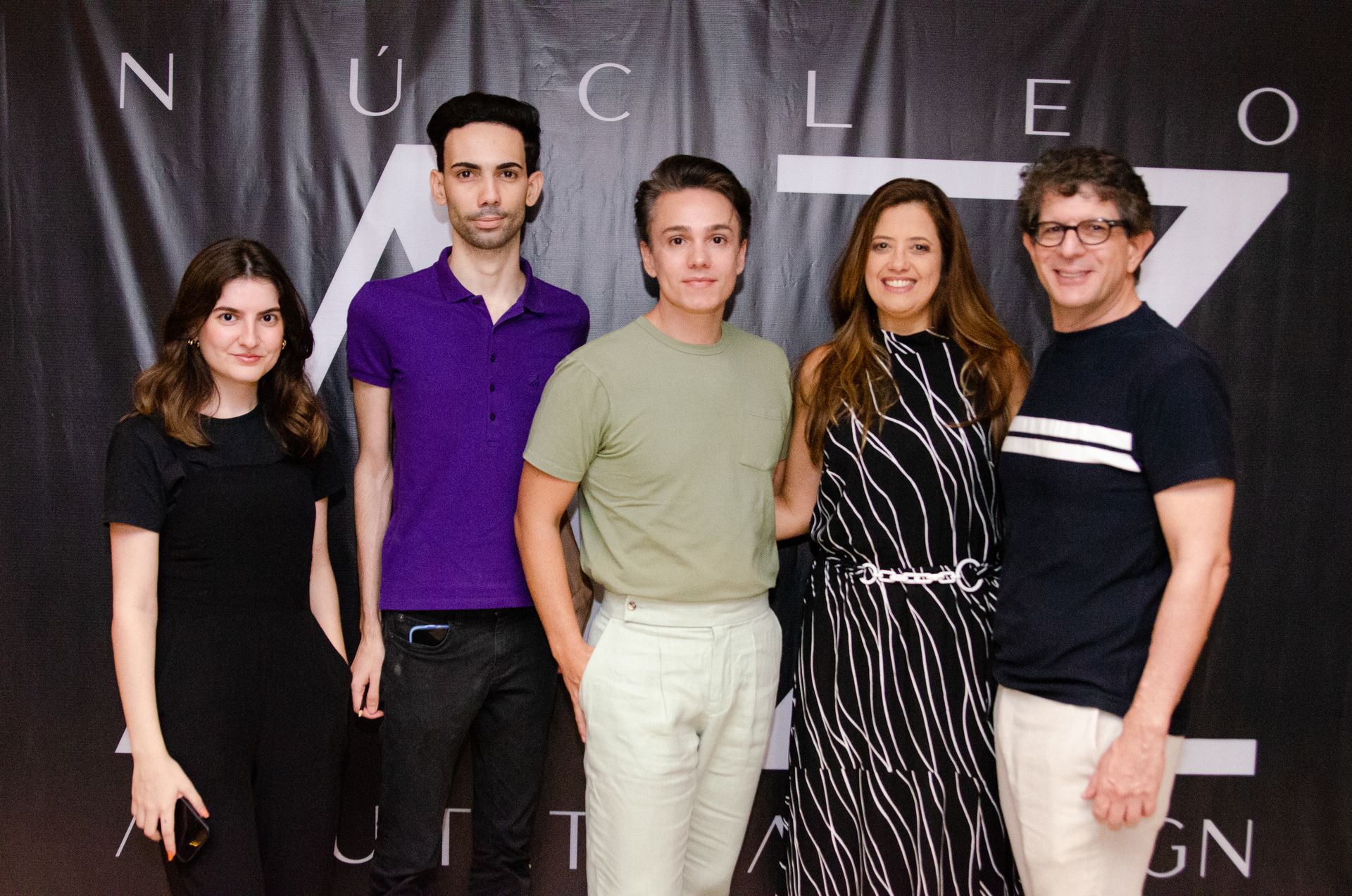 Um grupo de pessoas em pé em frente a uma placa que diz nucleo