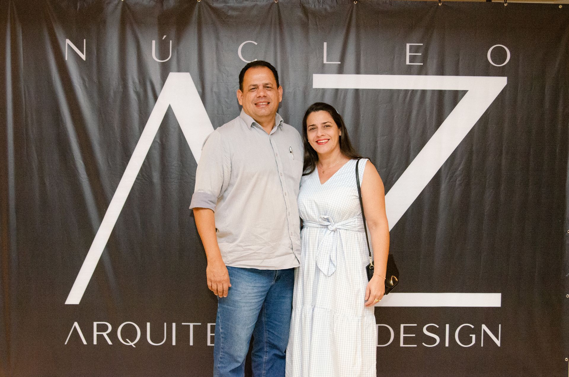 Um homem e uma mulher estão posando para uma foto em frente a uma placa que diz arquitet design