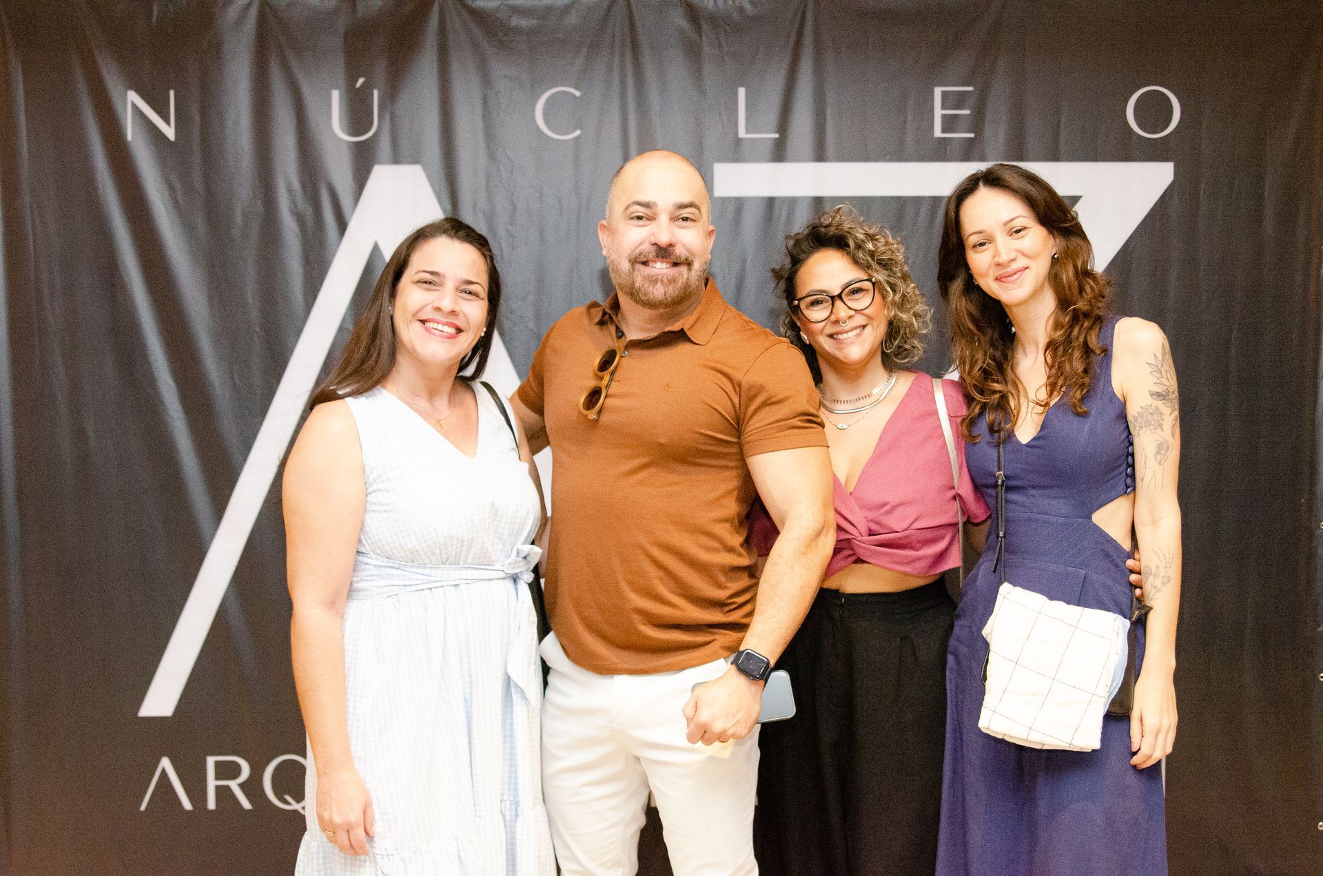 Um grupo de pessoas posando para uma foto em frente a uma placa que diz nucleo