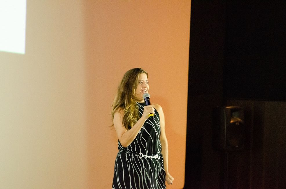 Uma mulher com um vestido listrado está parada em frente a um microfone.