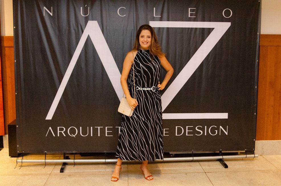 Uma mulher em um vestido preto e branco está parada em frente a uma placa que diz arquitetura design