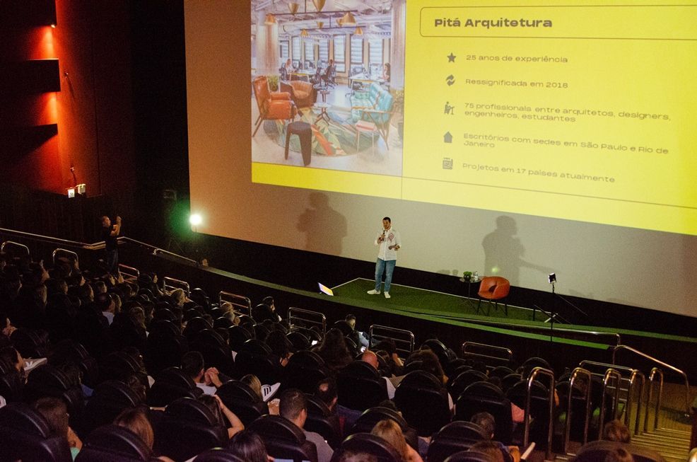 Um homem está fazendo uma apresentação para um grande grupo de pessoas em um teatro.