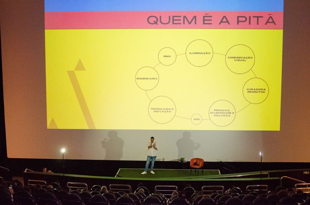 Um homem está em frente a uma tela grande que diz quem e a pita