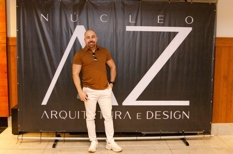 Um homem em pé na frente de uma faixa que diz núcleo arquitetura e design