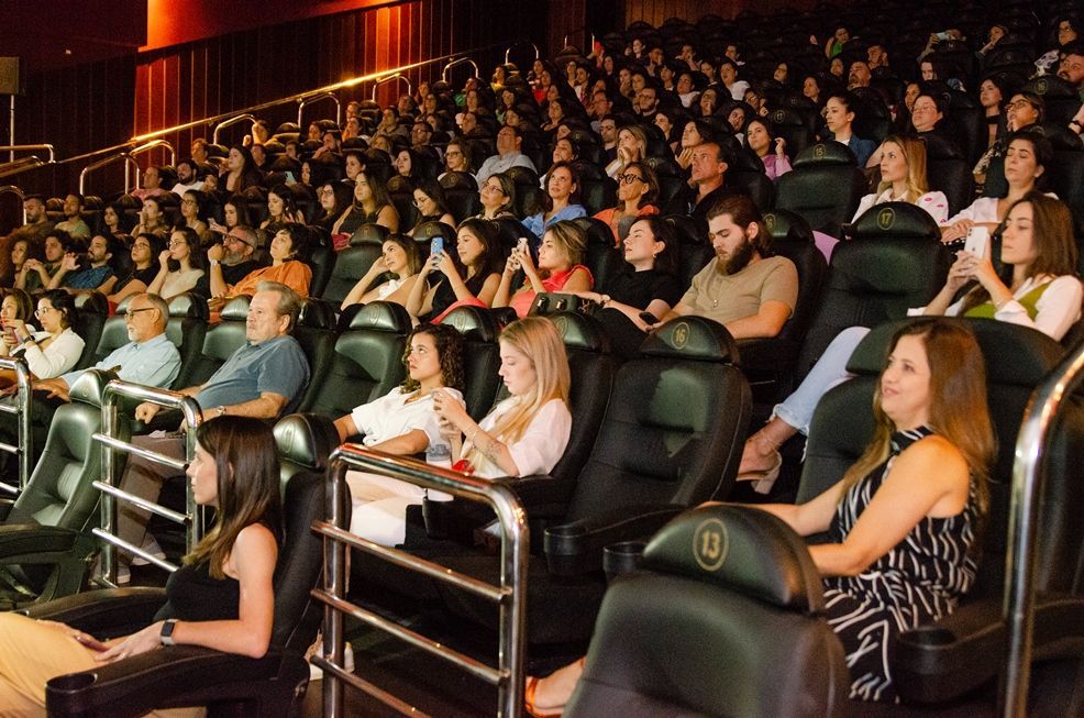 Um grande grupo de pessoas está sentado em um teatro assistindo a um filme