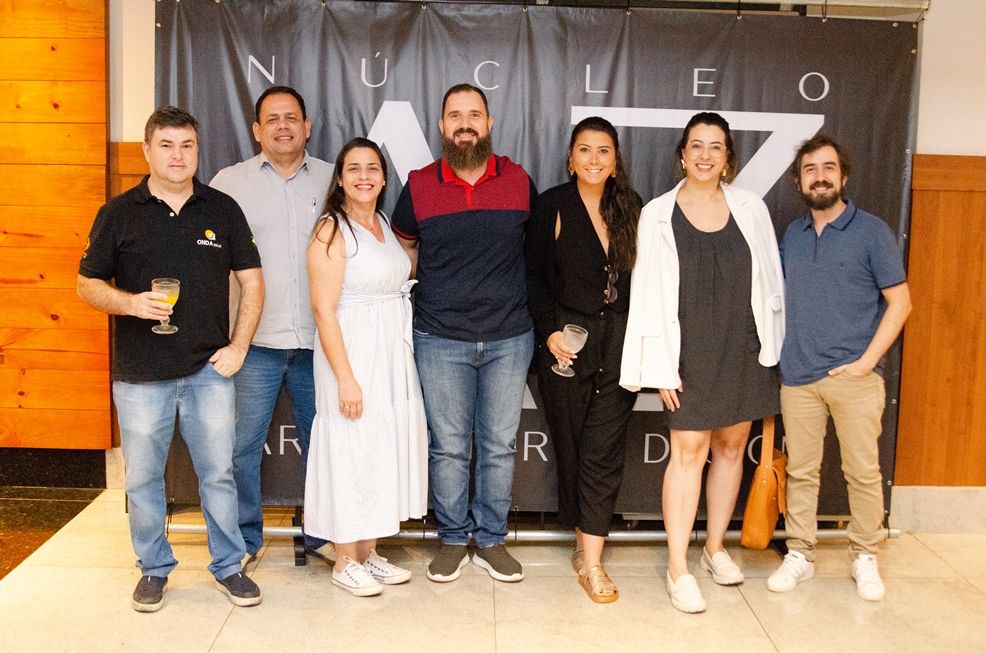 Um grupo de pessoas está posando para uma foto em frente a um banner.