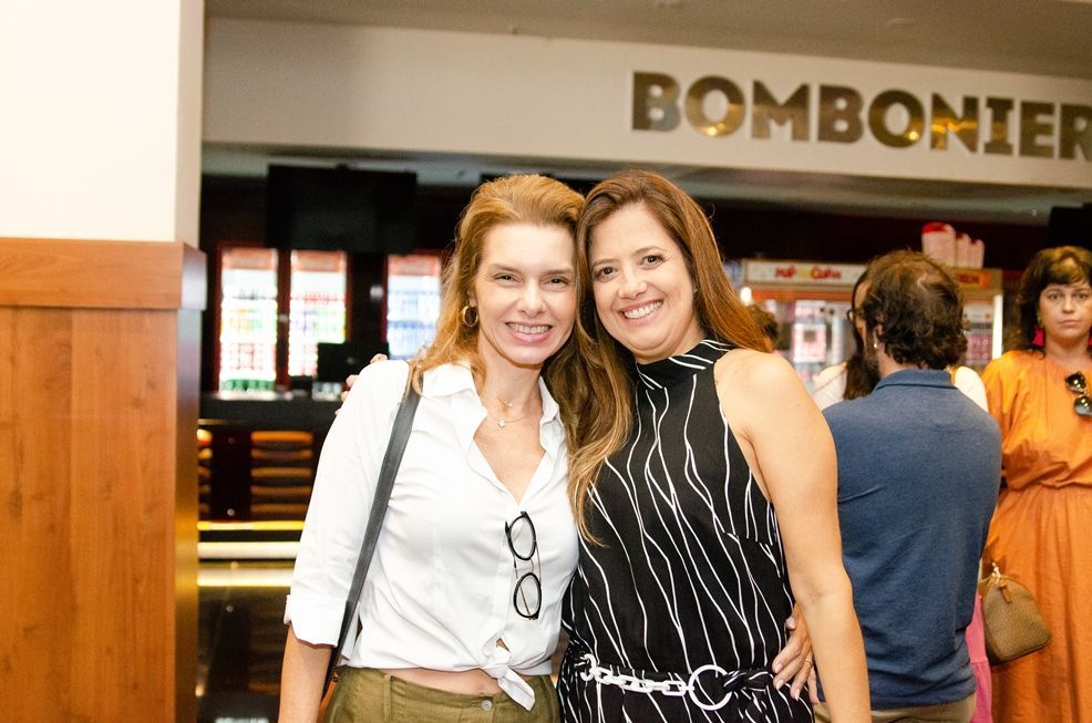 Duas mulheres estão posando para uma foto em frente a uma loja.
