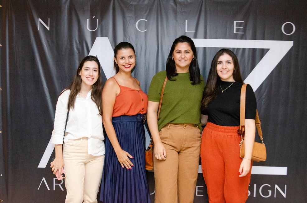 Um grupo de mulheres está posando para uma foto em frente a uma placa.