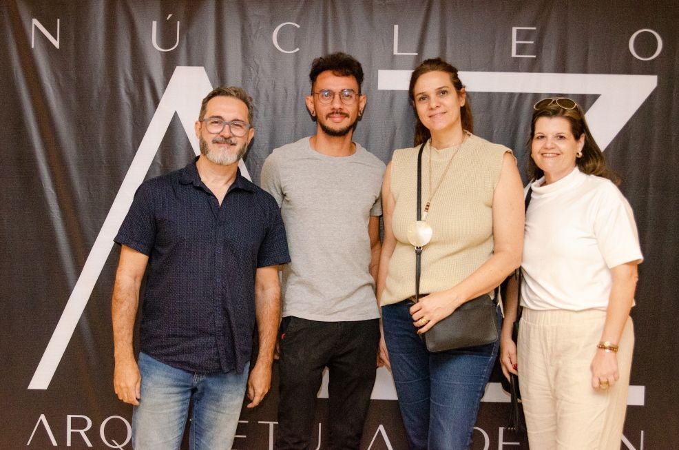 Um grupo de pessoas em pé em frente a uma placa que diz nucleo