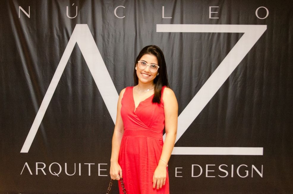 Uma mulher de vestido vermelho está em frente a uma placa que diz arquitete design