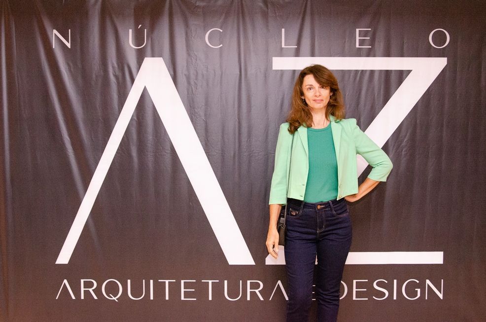 Uma mulher com uma jaqueta verde está em frente a uma placa que diz arquitetura design