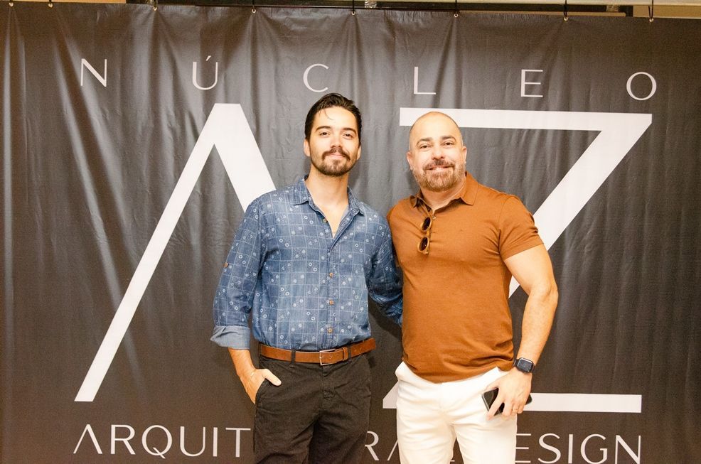 Dois homens estão posando para uma foto em frente a uma placa que diz arquit design