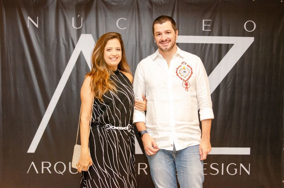 Um homem e uma mulher estão posando para uma foto em frente a uma placa que diz nucleo