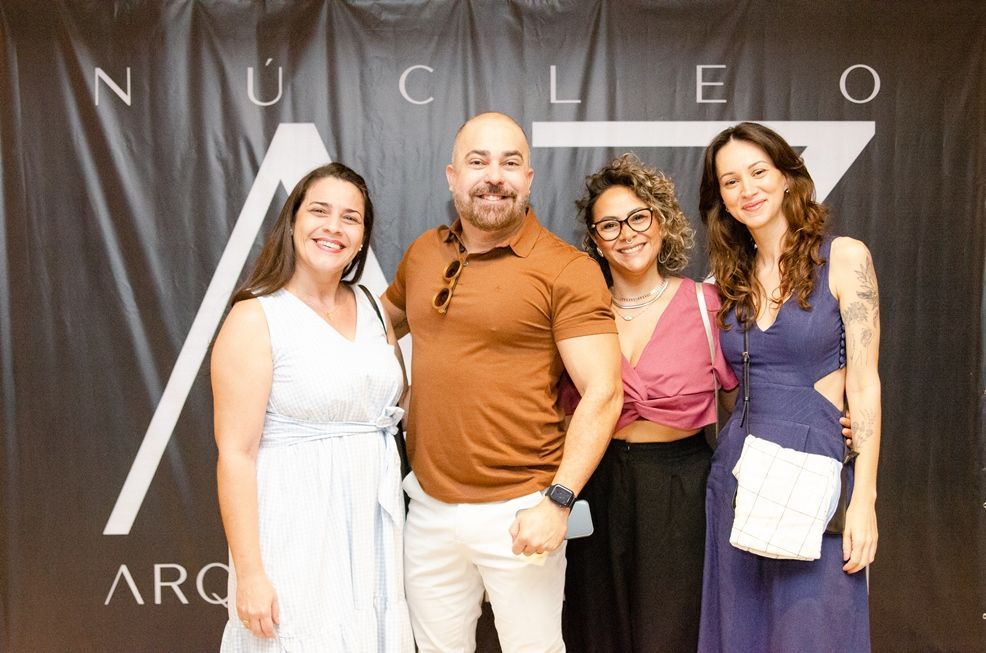 Um grupo de pessoas está posando para uma foto em frente a uma placa.
