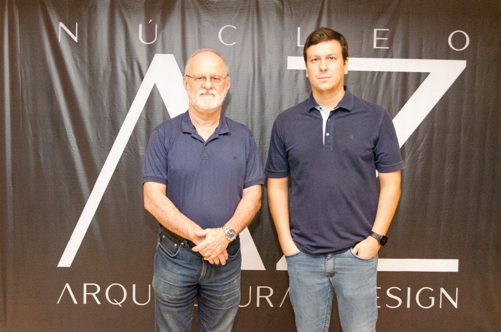 Dois homens parados em frente a uma placa que diz nucleo