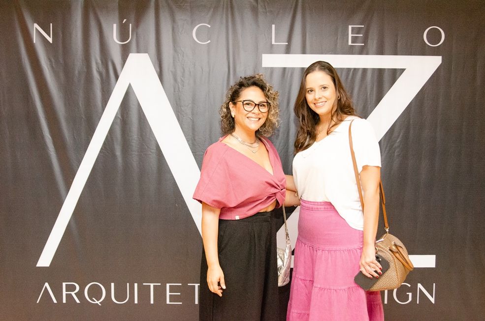 Duas mulheres posam para uma foto em frente a uma placa que diz nucleo