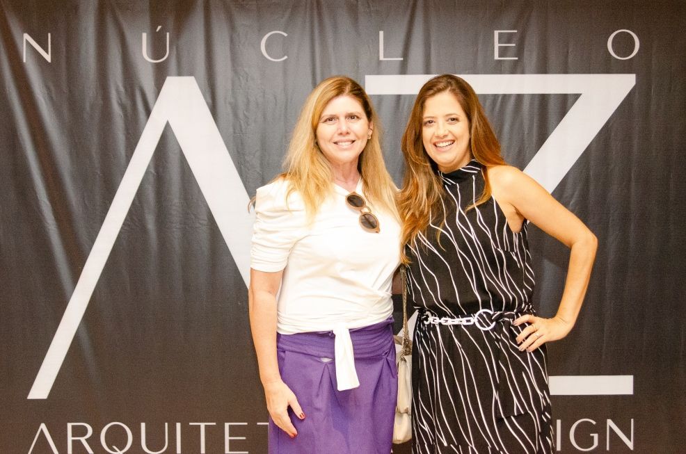 Duas mulheres em pé na frente de uma placa que diz nucleo