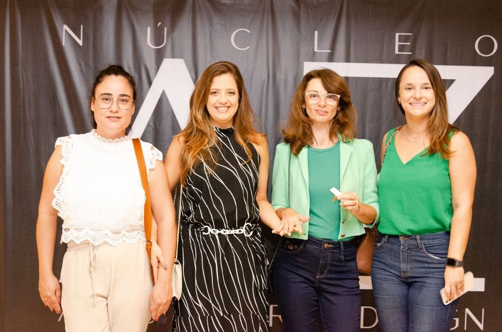 Um grupo de mulheres está posando para uma foto em frente a uma faixa.