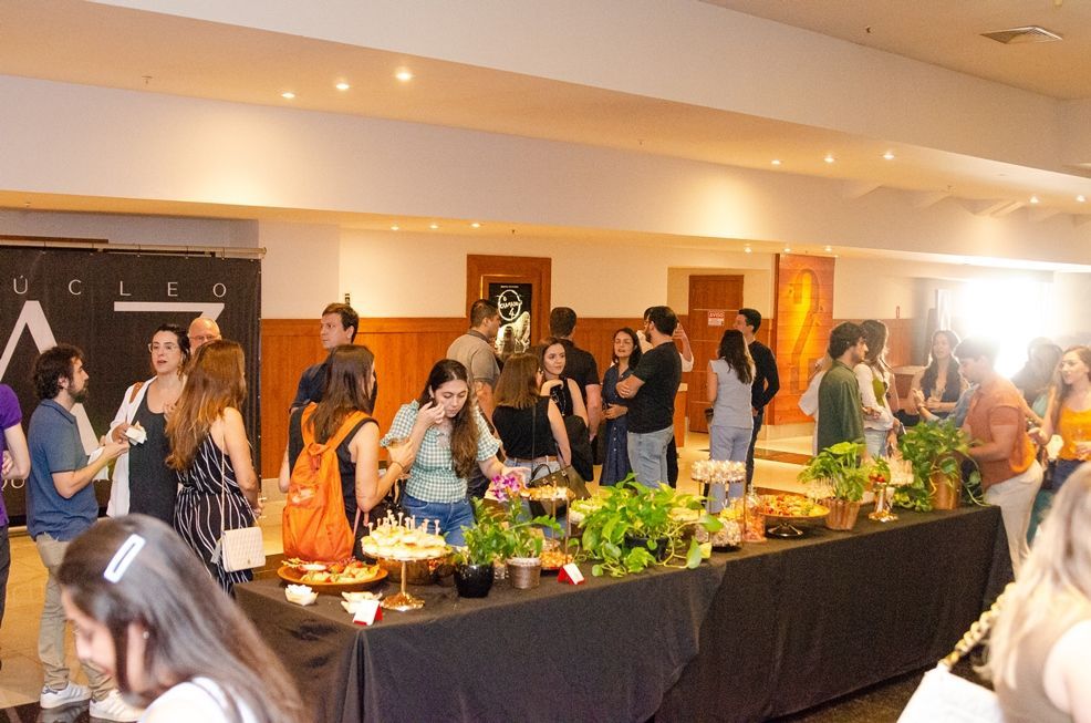 Um grupo de pessoas está em pé ao redor de uma mesa de bufê em uma sala.
