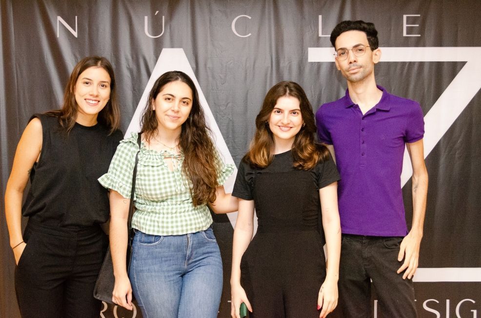Um grupo de pessoas está posando para uma foto em frente a um fundo preto.