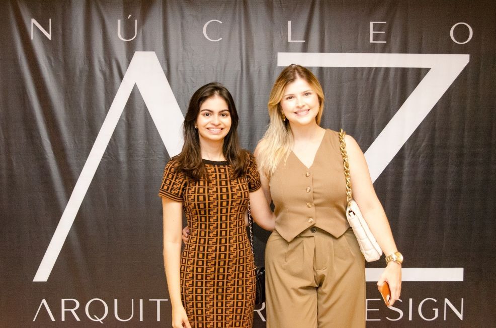 Duas mulheres em pé na frente de uma placa que diz nucleo