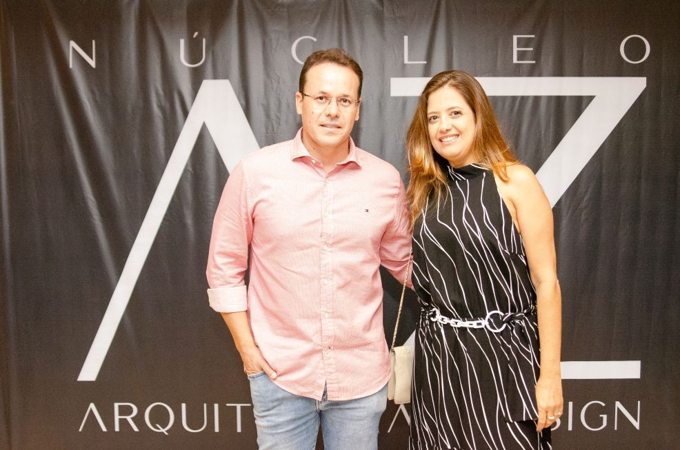 Um homem e uma mulher posam para uma foto em frente a uma placa que diz arquiteto
