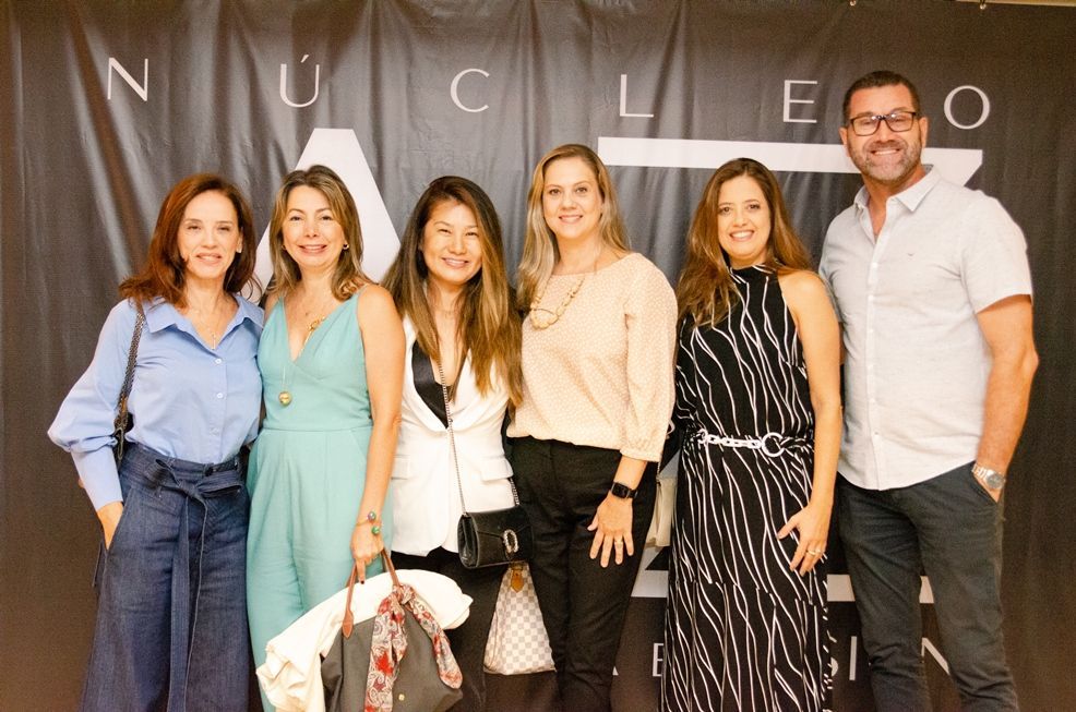 Um grupo de pessoas está posando para uma foto em frente a uma faixa que diz nucleo.