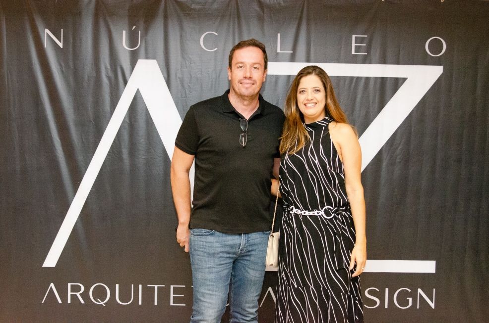 Um homem e uma mulher estão posando em frente a uma placa que diz arquitet