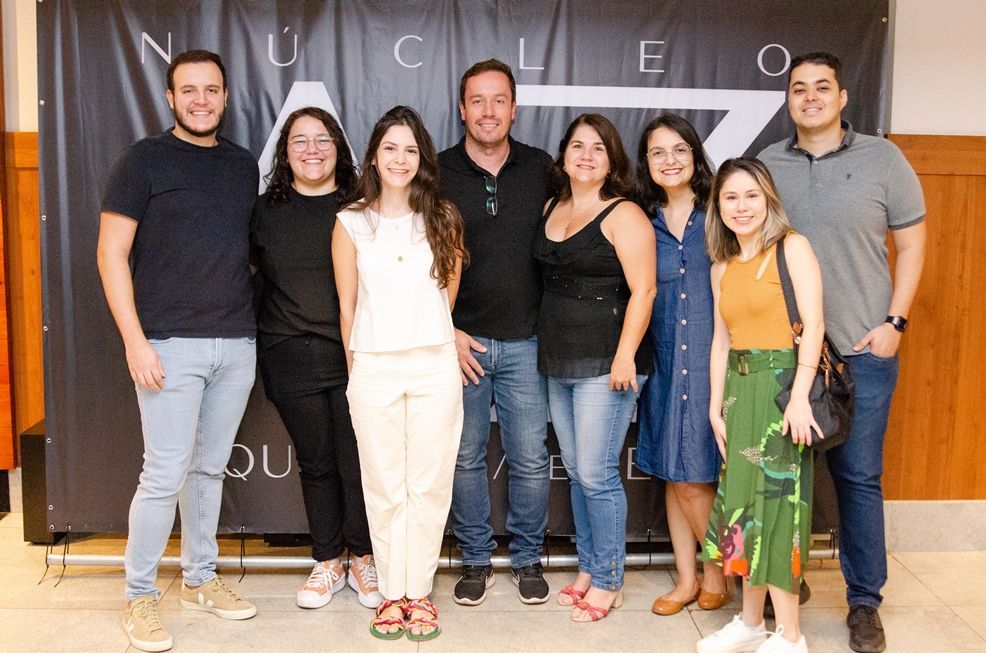Um grupo de pessoas está posando para uma foto em frente a um banner.