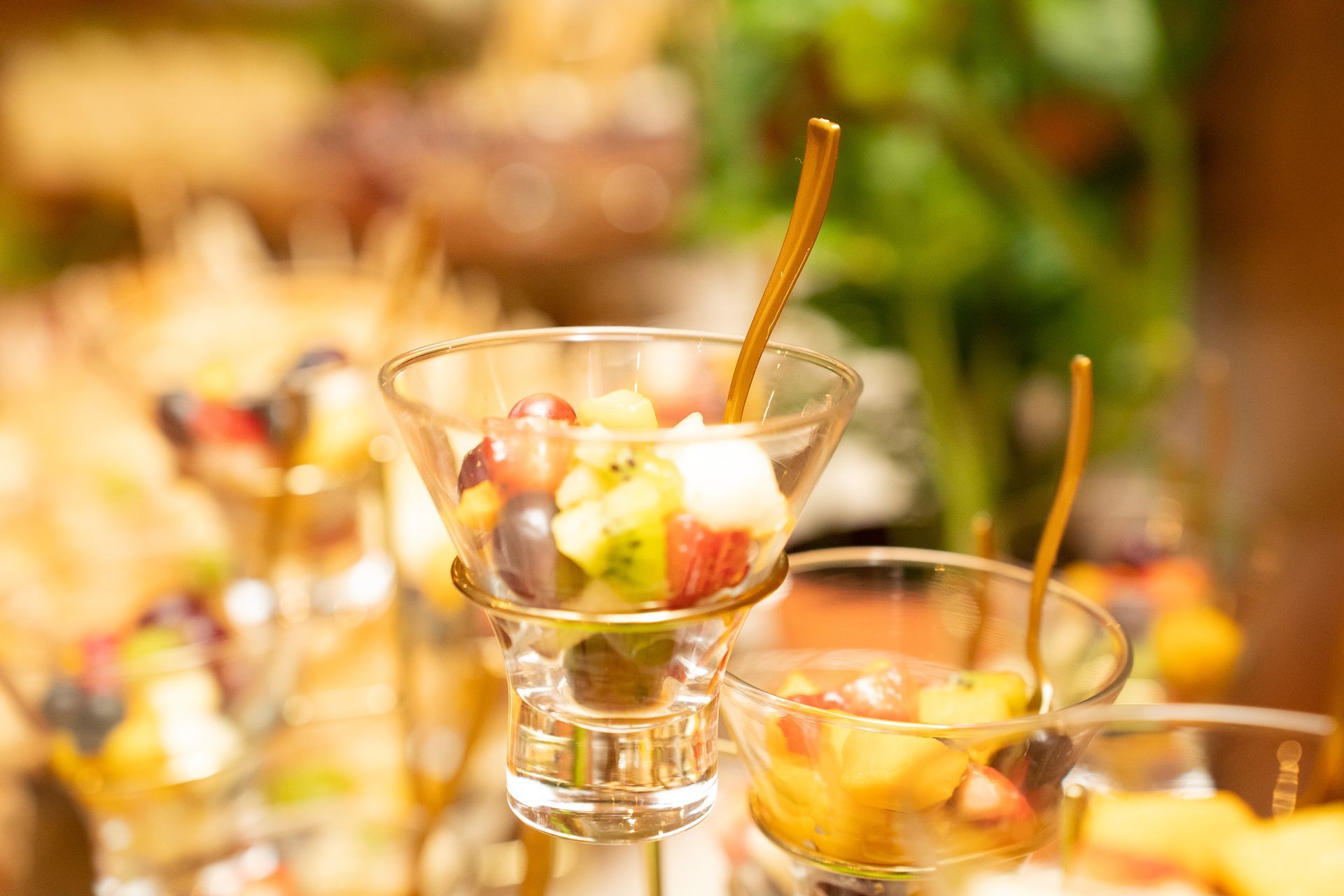 Uma taça de martini cheia de frutas e uma colher dentro dela.