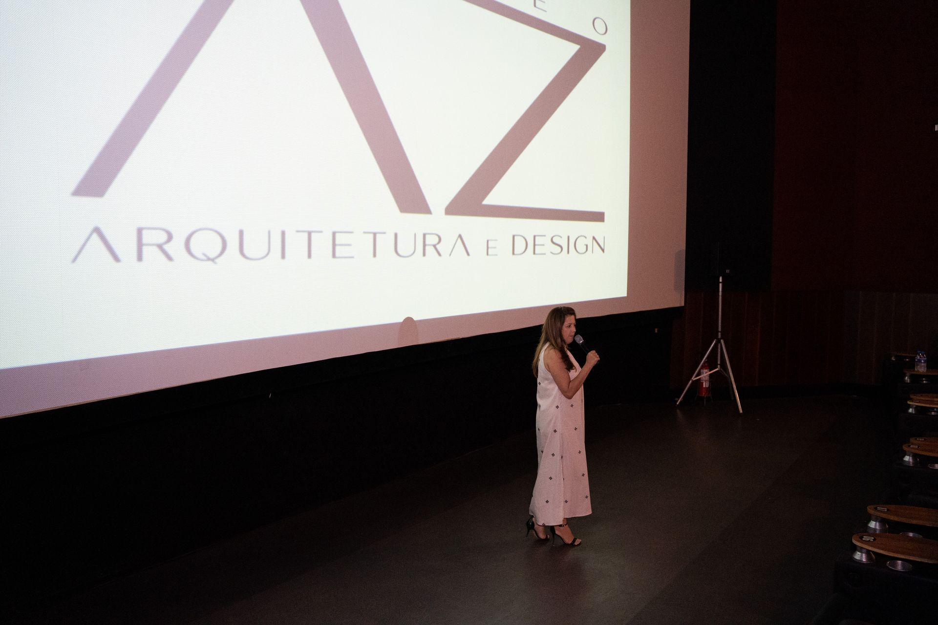 Uma mulher está parada em frente a uma tela grande que diz arquitetura e design