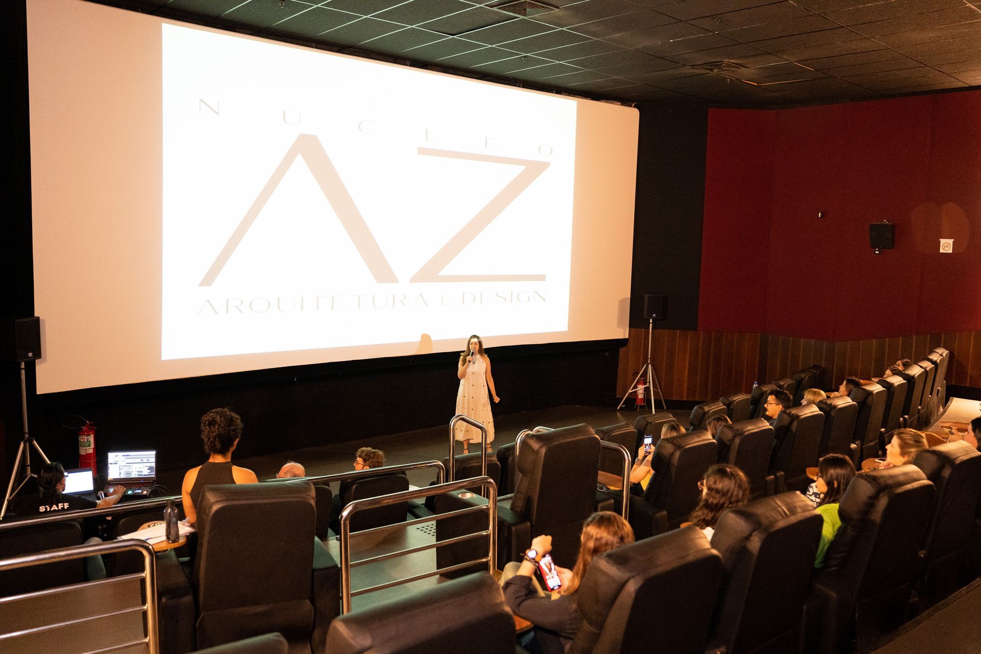 Uma mulher está fazendo uma apresentação em frente a uma tela que diz az