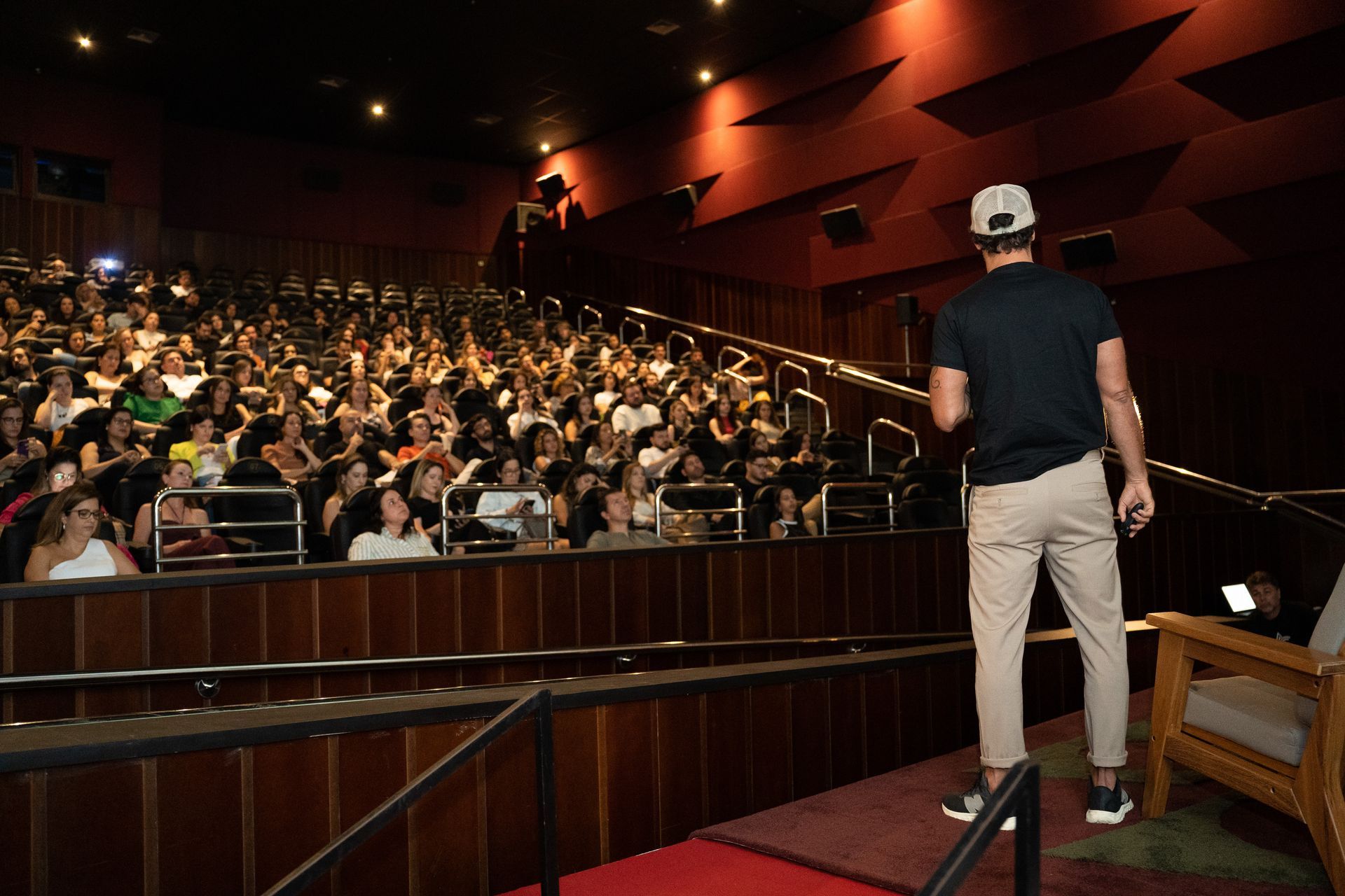 Um homem está em pé em um palco em frente a uma multidão de pessoas em um auditório.