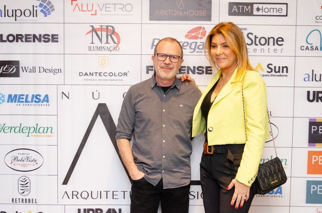 Um homem e uma mulher estão posando para uma foto em frente a uma parede de logotipos.