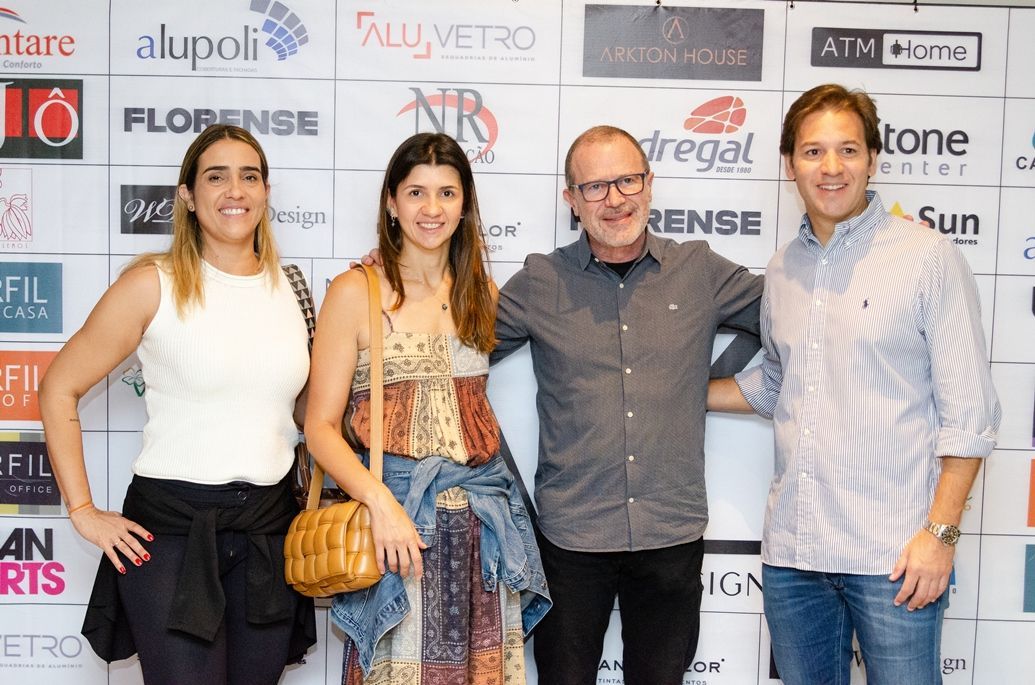 Um grupo de pessoas posando para uma foto em frente a uma parede com logotipos