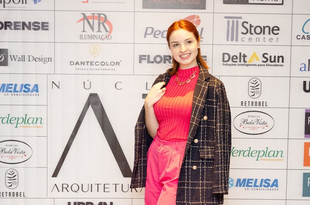 Uma mulher está parada em frente a uma parede com logotipos.