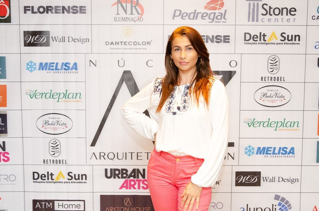 Uma mulher está parada em frente a uma parede com logotipos