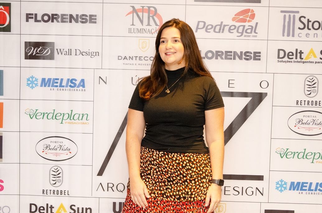 Uma mulher está parada em frente a uma parede com logotipos