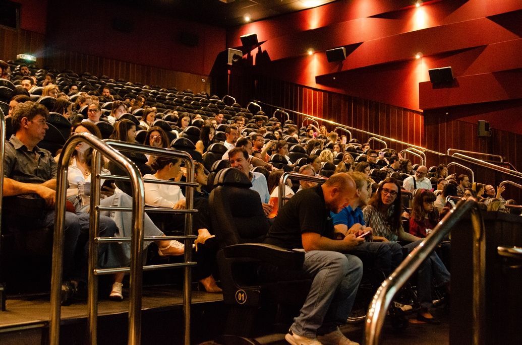 Uma multidão de pessoas está sentada em um cinema assistindo a um filme.