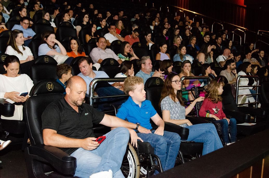 Um grupo de pessoas está sentado em um teatro assistindo a um filme
