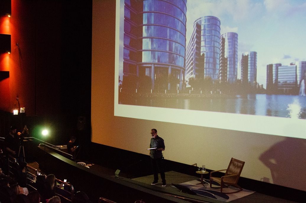 Um homem está fazendo uma apresentação em frente a uma tela grande