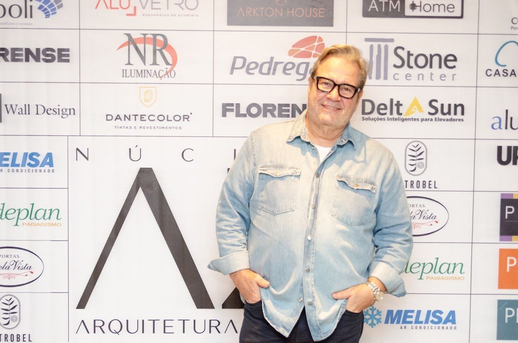 Um homem parado em frente a uma parede com logotipos nela