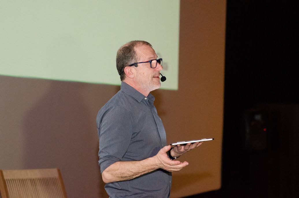Um homem usando óculos e um microfone está segurando um tablet.