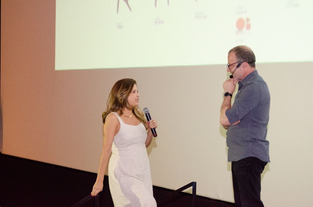 Um homem e uma mulher estão de pé, um ao lado do outro, falando em microfones.