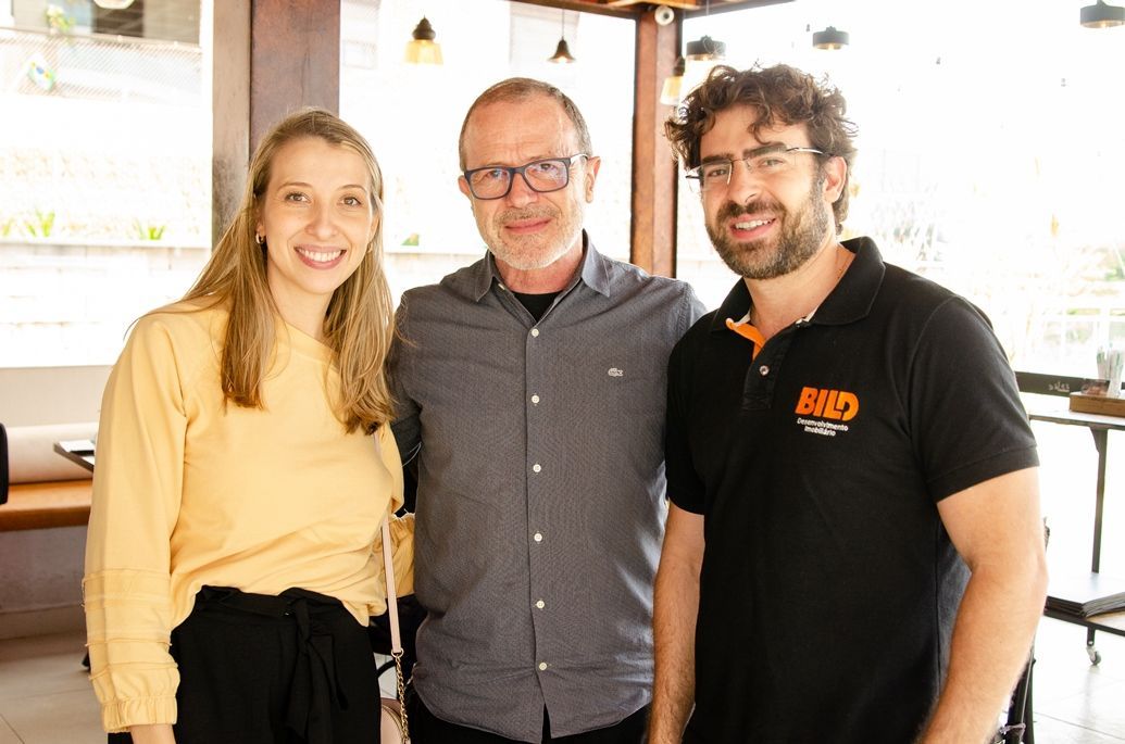Um homem e duas mulheres estão posando para uma foto em um restaurante.