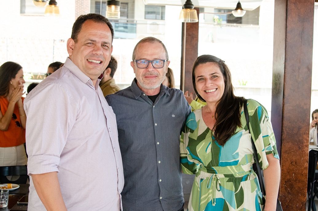 Três pessoas estão posando para uma foto juntas em um restaurante.